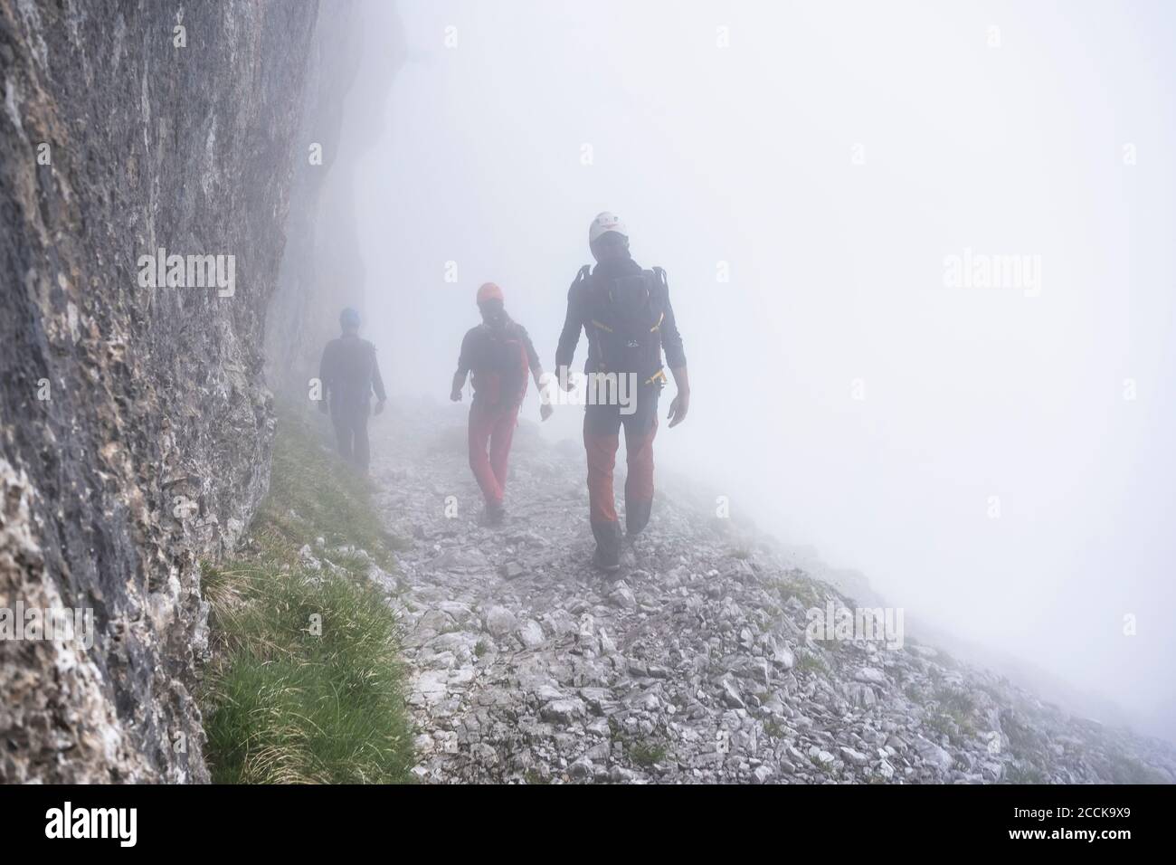 Uomini maturi che camminano in montagna durante il tempo foggoso, Alpi Bergamasche, Italia Foto Stock