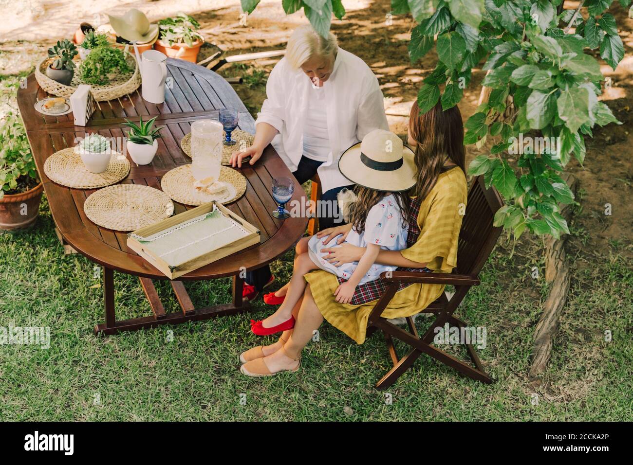 Famiglia multigenerativa che gode di picnic al tavolo in cortile Foto Stock