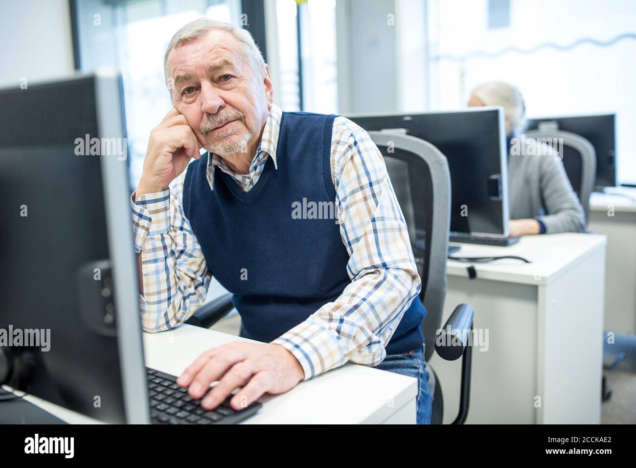 Uomo anziano che frequenta il corso del calcolatore, osservante helpless Foto Stock