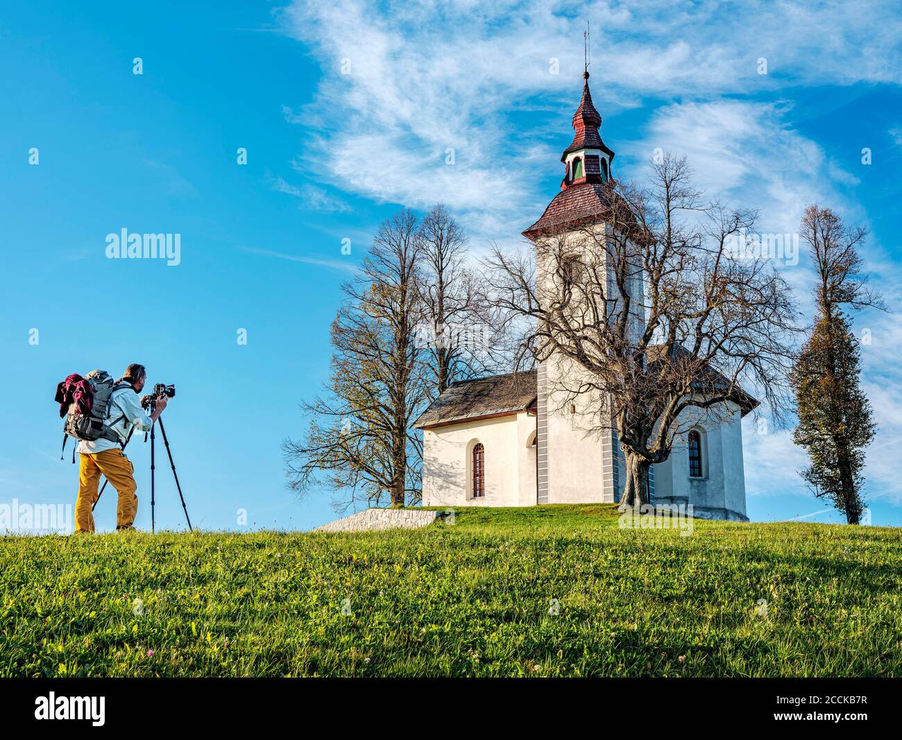 Slovenia, alta Carniola, comune di Skofja Loka, uomo che fotografa la Chiesa di San Thomass in autunno Foto Stock
