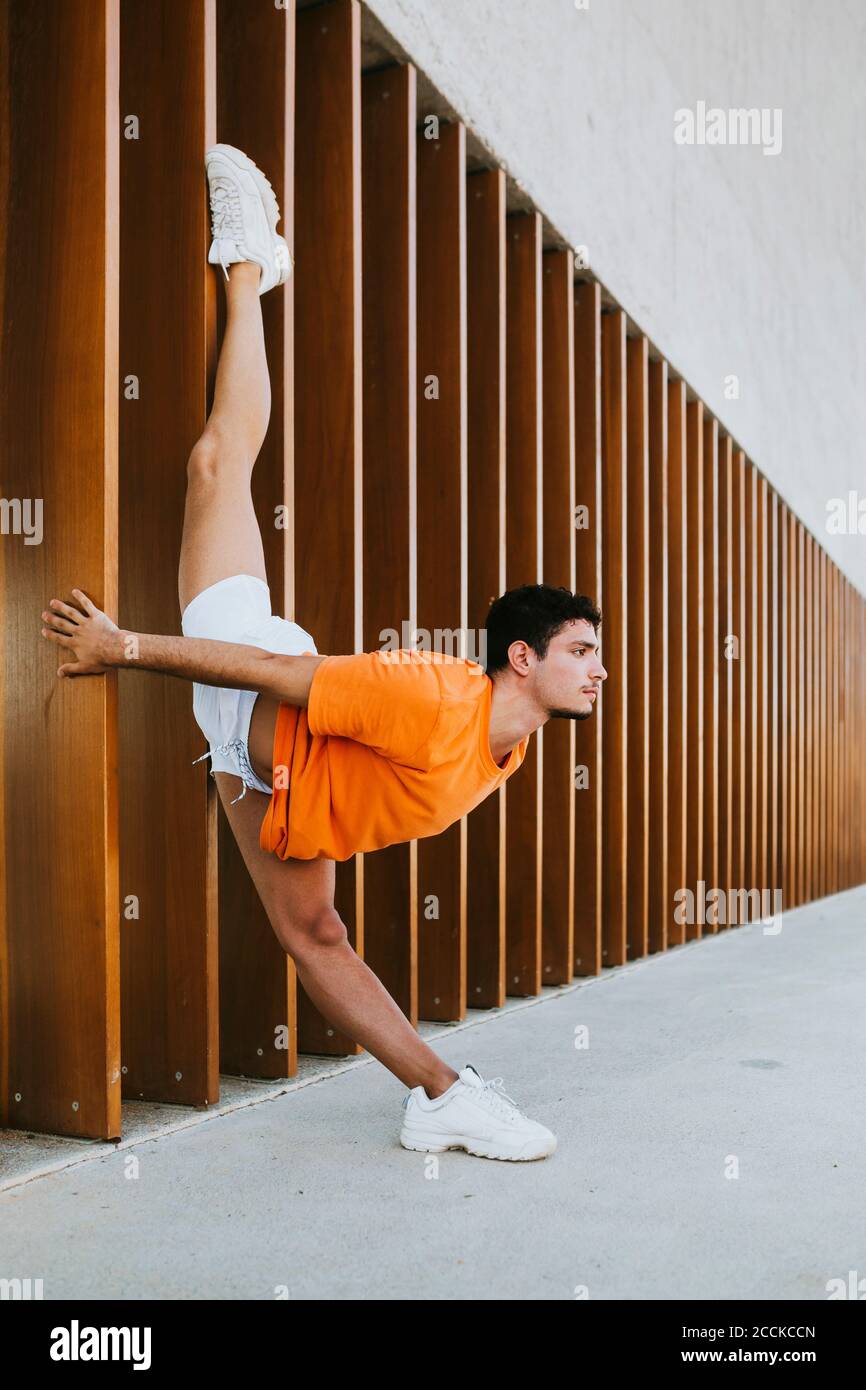 Giovane uomo che fa esercizio di ginnastica ritmica da struttura integrata città Foto Stock