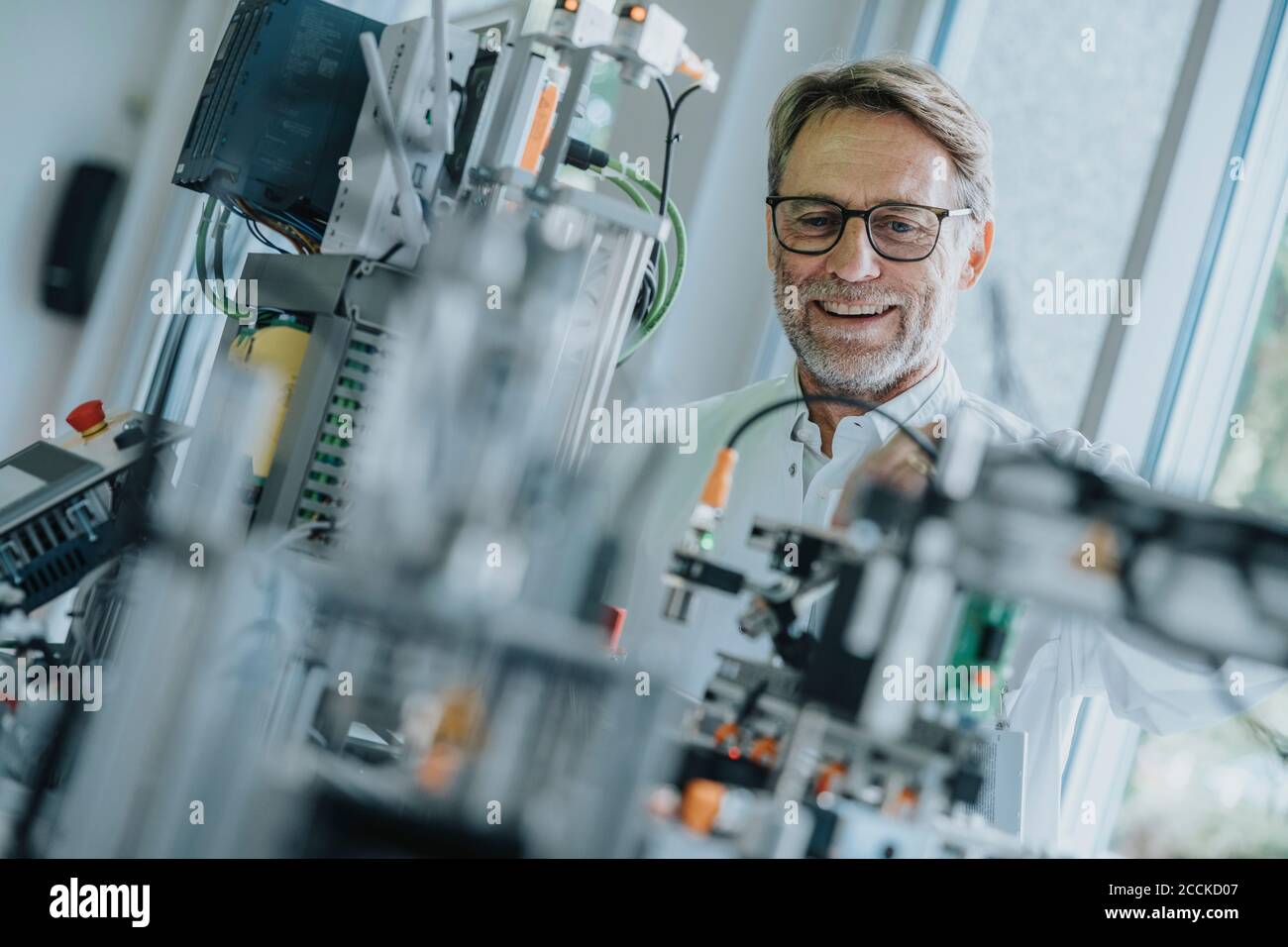 Sorridente ingegnere maschile che esamina le attrezzature in laboratorio Foto Stock