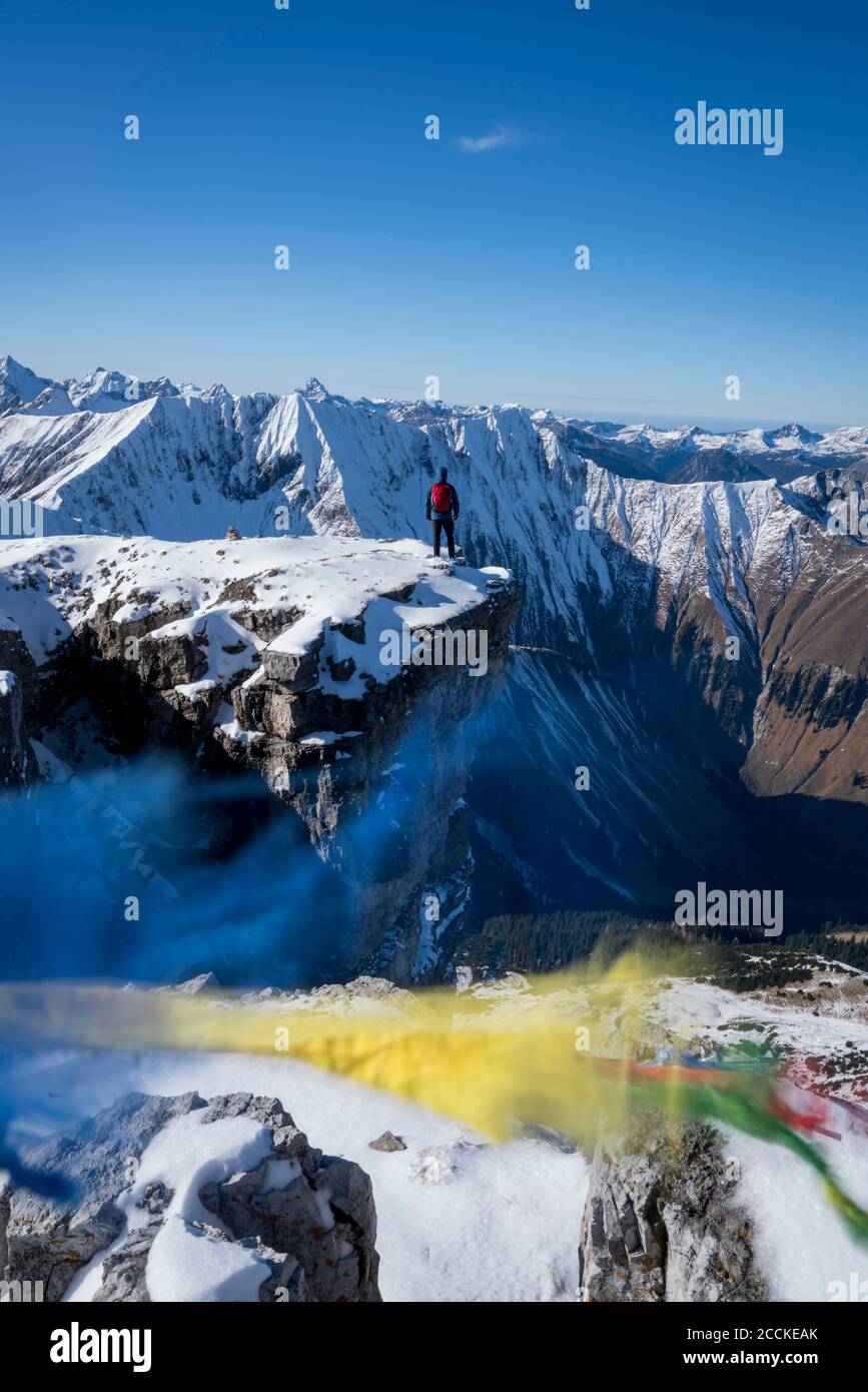 Escursionista maschile in piedi al bordo di Namloser Wetterspitze picco con fumo colorato che sorge sotto Foto Stock