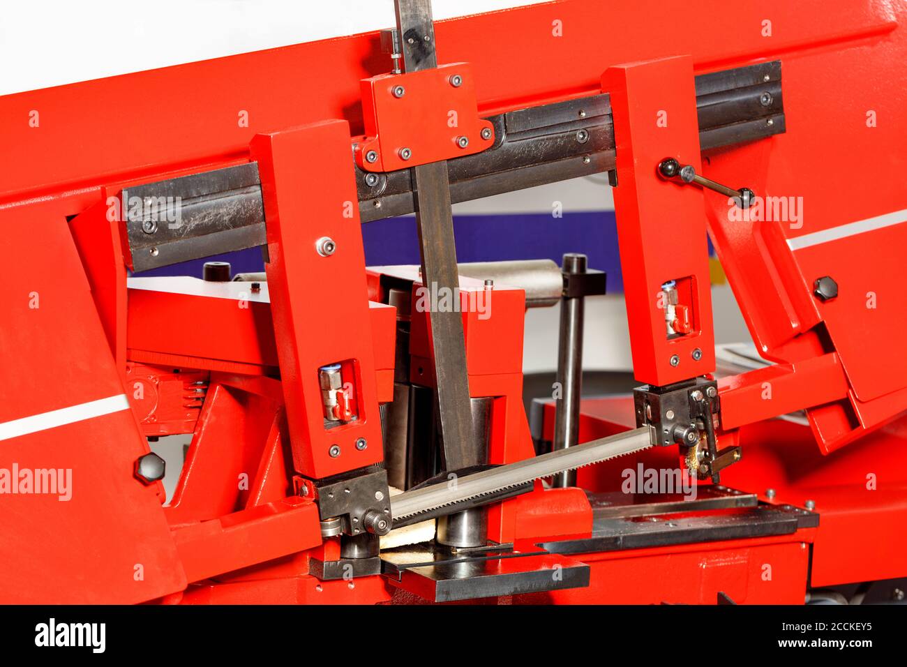 I denti affilati della sega a nastro sulla moderna macchina per la lavorazione dei metalli rossi garantiscono un'elevata precisione di taglio grazie alla linea di regolazione. Primo piano. Foto Stock