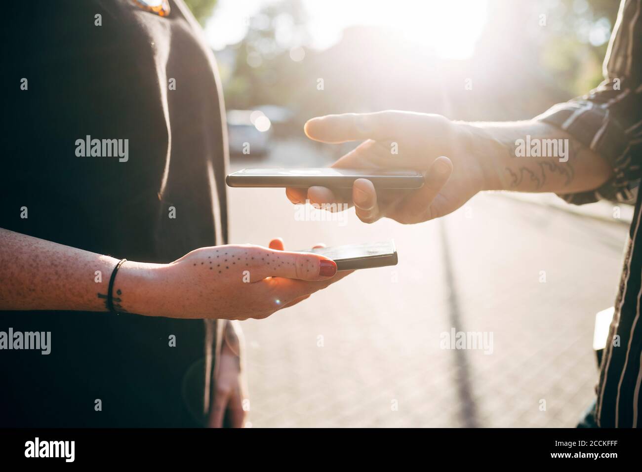 Primo piano del codice di scansione di coppia tramite smartphone in città durante il giorno di sole Foto Stock