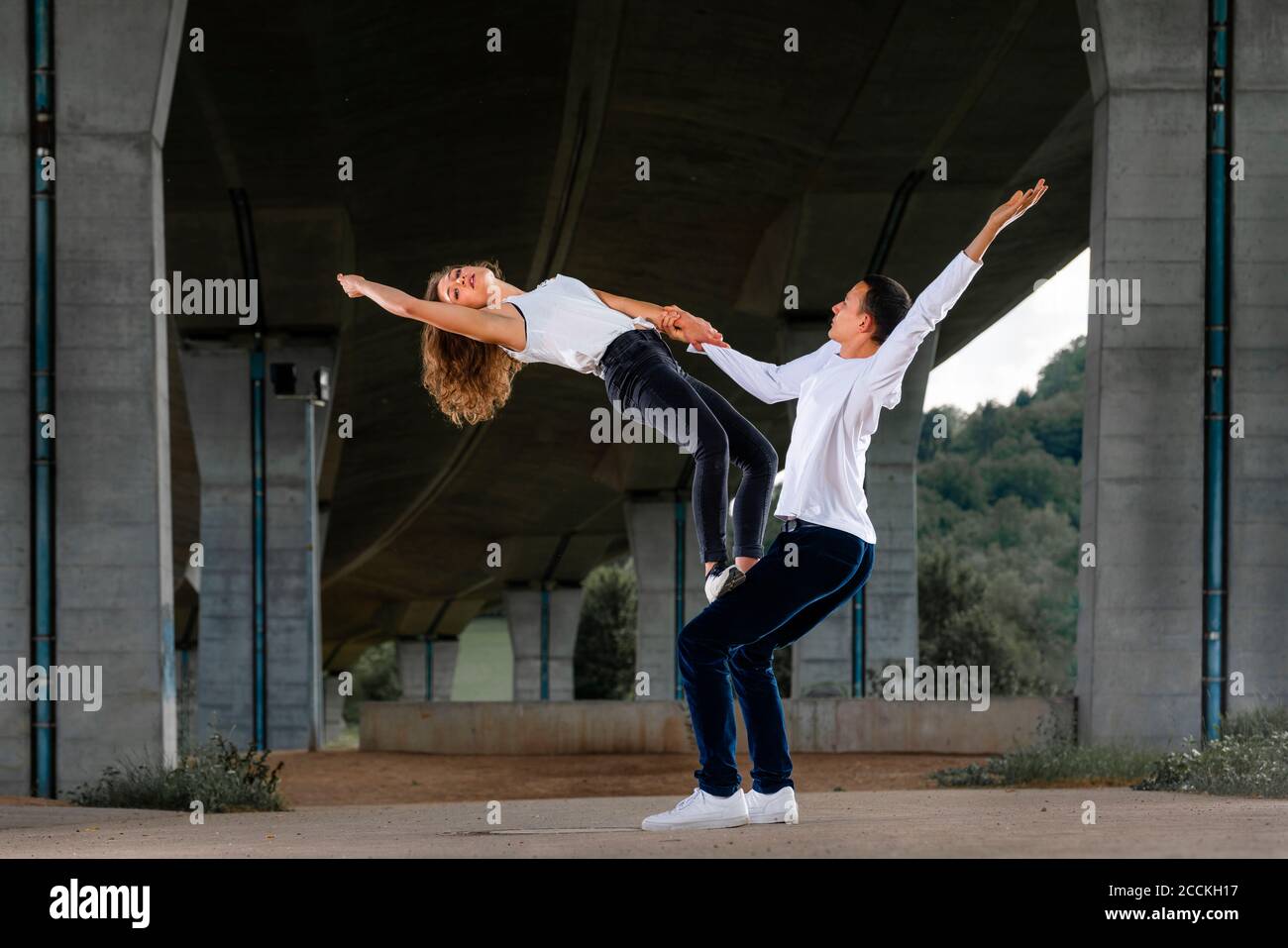 Amici di sesso maschile e femminile che praticano aerobica su strada sotto il ponte Foto Stock