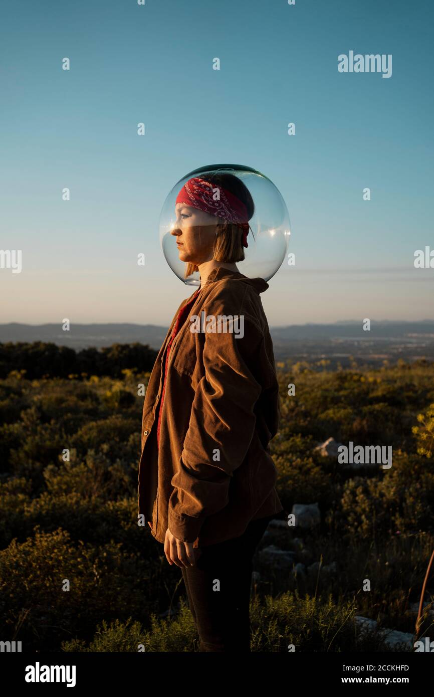 Donna con una ciotola di pesce sulla testa in campagna Foto Stock