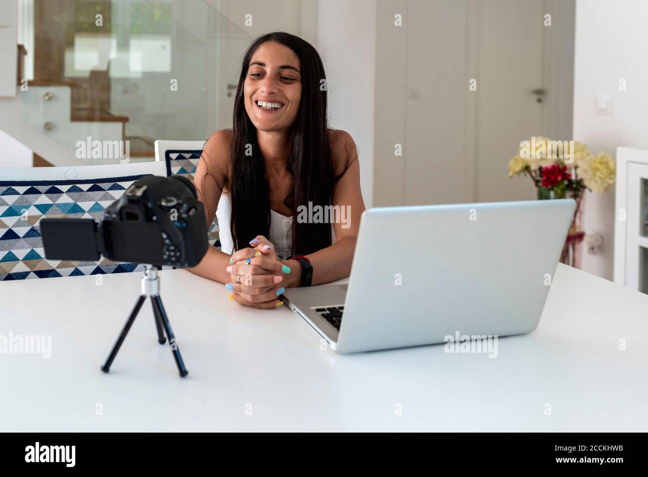 Blogger femmina registrazione video con fotocamera sul tavolo a casa Foto Stock