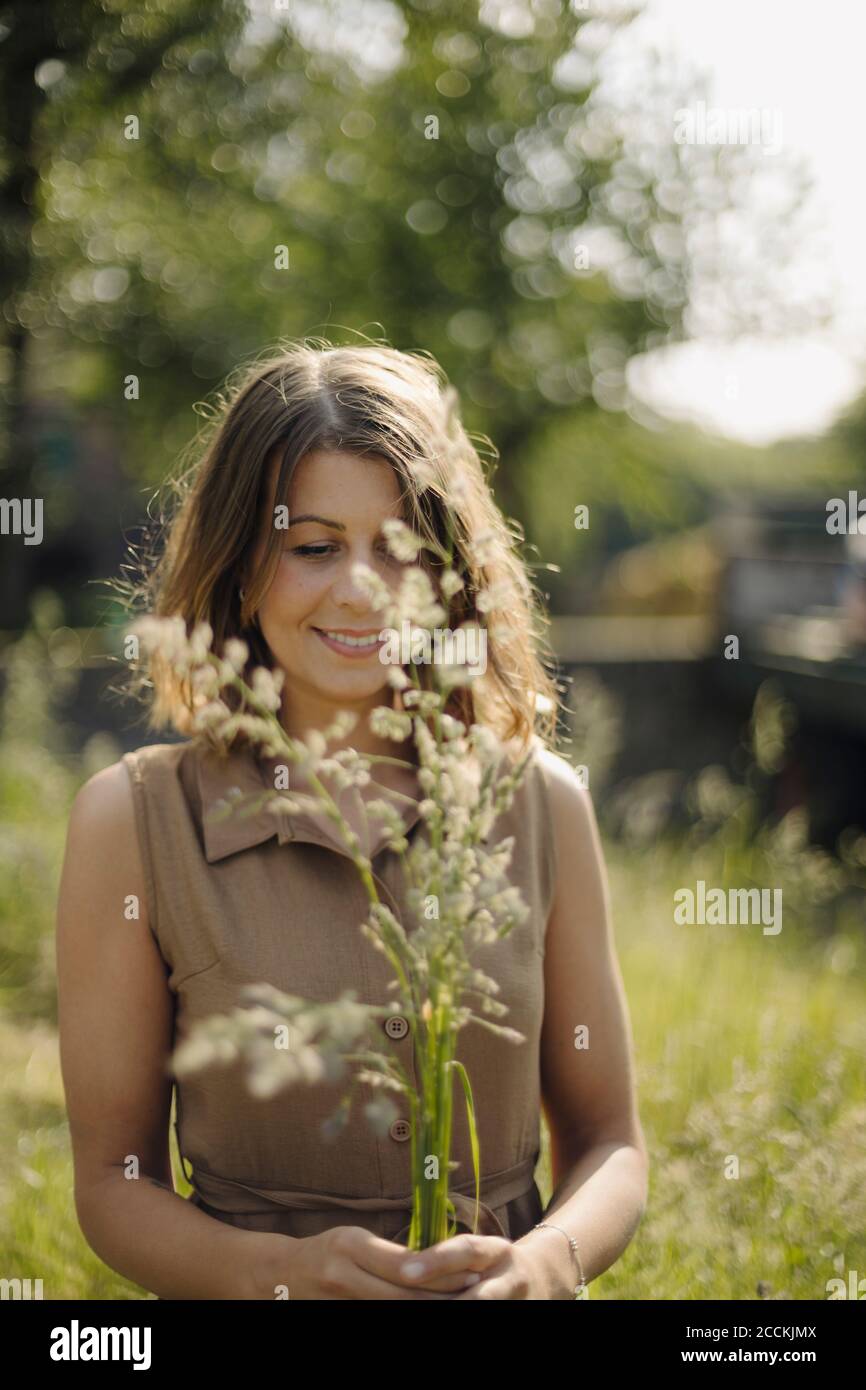 Giovane donna che tiene piante d'erba in campagna Foto Stock