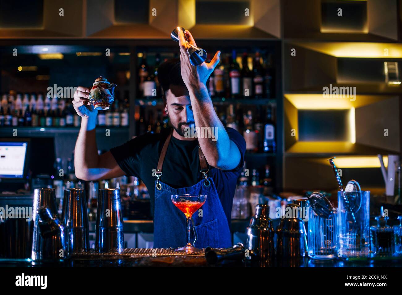 Barman maschile che effettua cocktail al banco bar del pub notte Foto Stock
