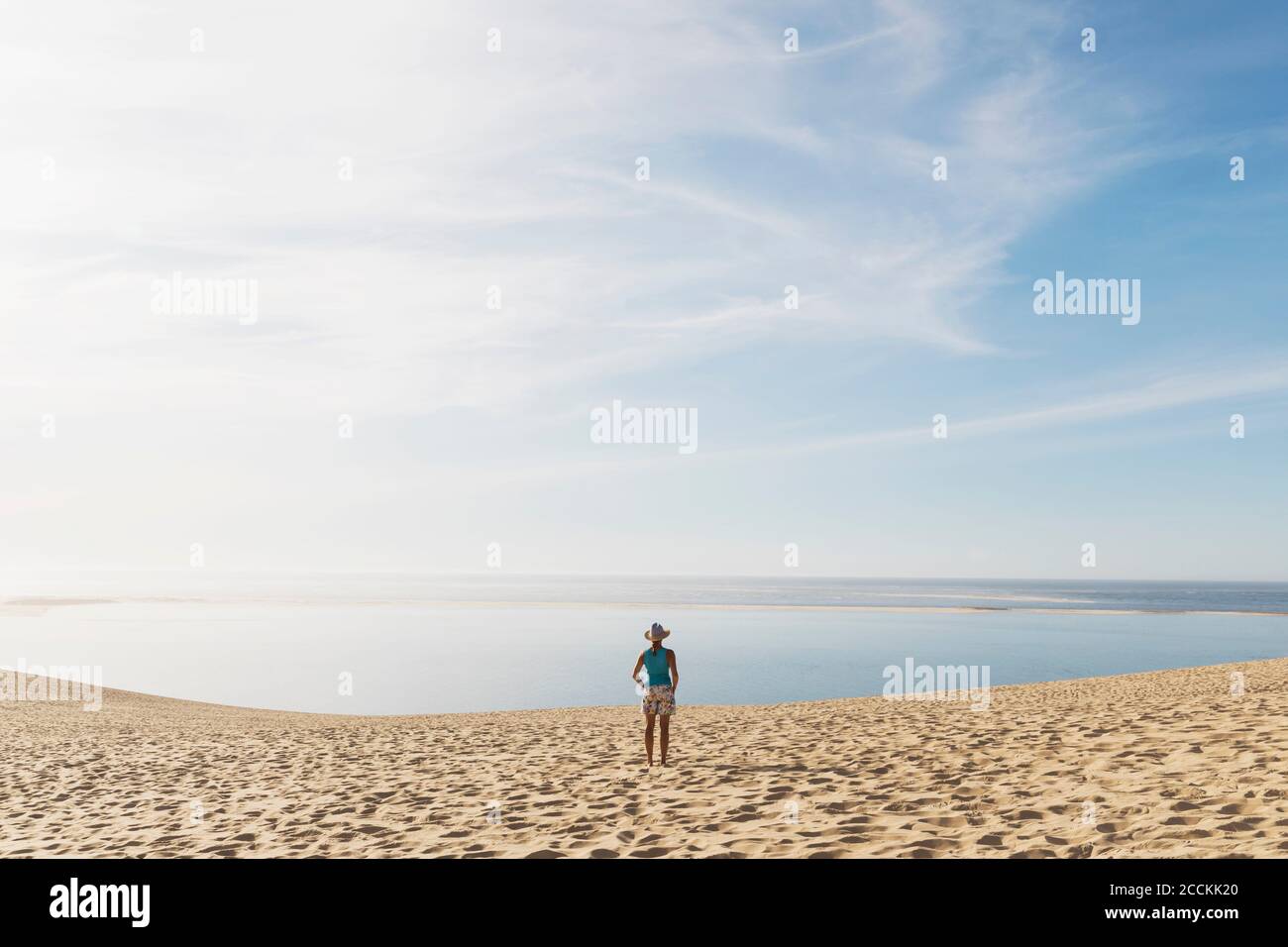 Donna che guarda l'oceano Atlantico mentre si trova sulla spiaggia durante il giorno di sole, Duna di Pilat, Nouvelle-Aquitaine, Francia Foto Stock