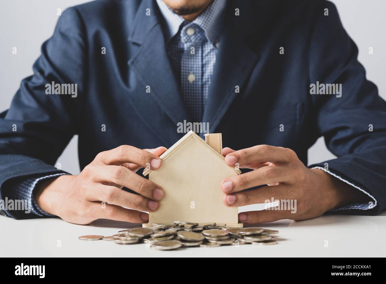 Mano di uomo di affari che tiene moneta messo in banca piggy con pila di denaro crescente crescita risparmio di denaro, concetto di investimento per il commercio di libertà finanziaria. Foto Stock