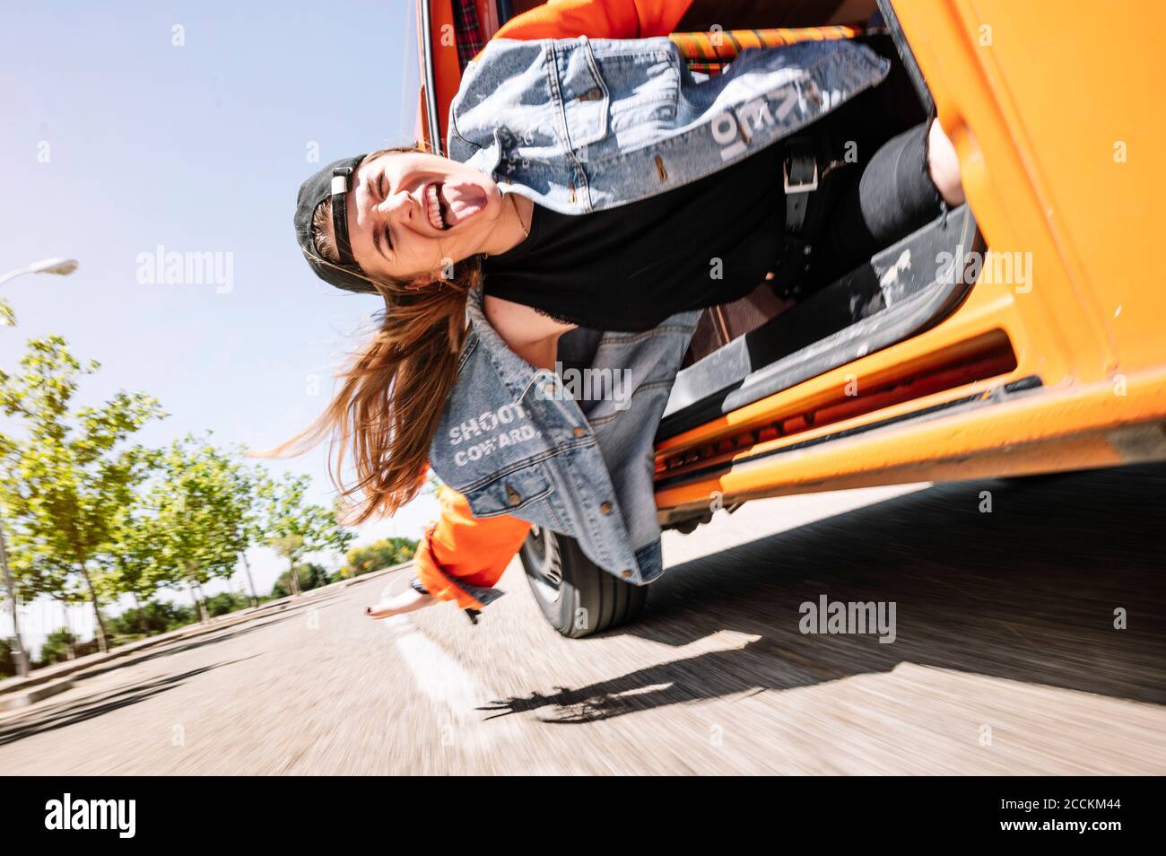 Giovane donna appesa alla guida dell'auto, attaccando la lingua fuori Foto Stock