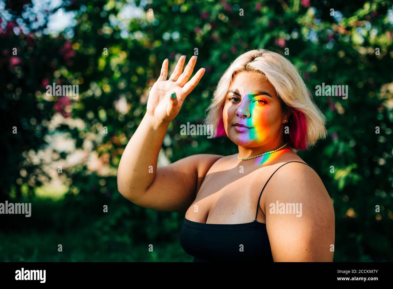 Donna che ferma il riflesso della luce con la mano al parco Foto Stock