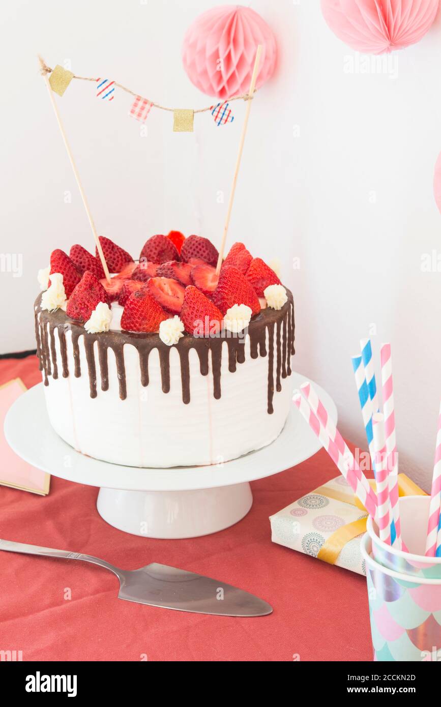 Torta con glassa, cioccolato e fragole sul tavolo da festa Foto Stock