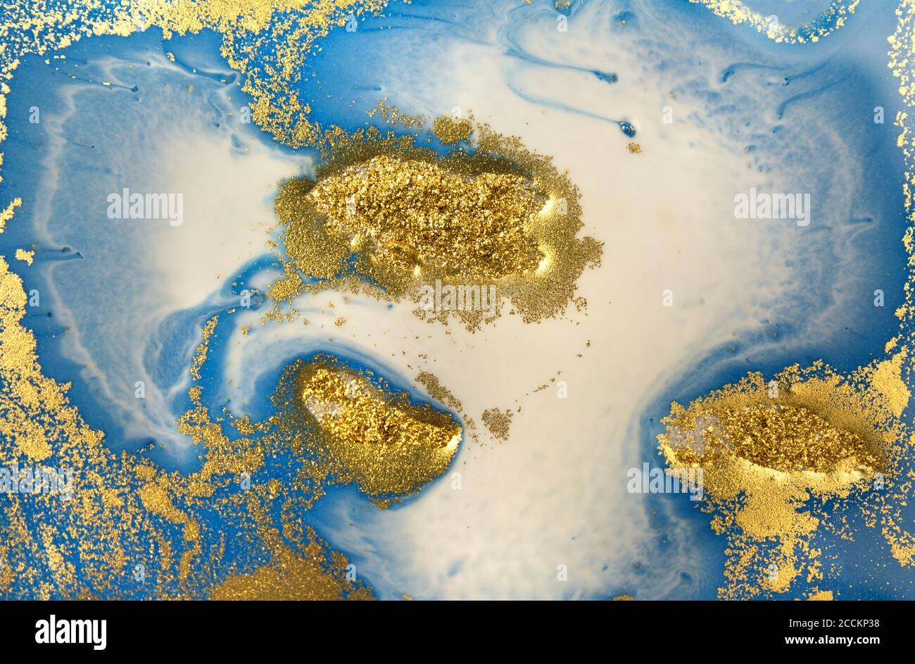 Pile di paillette d'oro su sfondo blu con inchiostro liquido. Modello astratto. Foto Stock