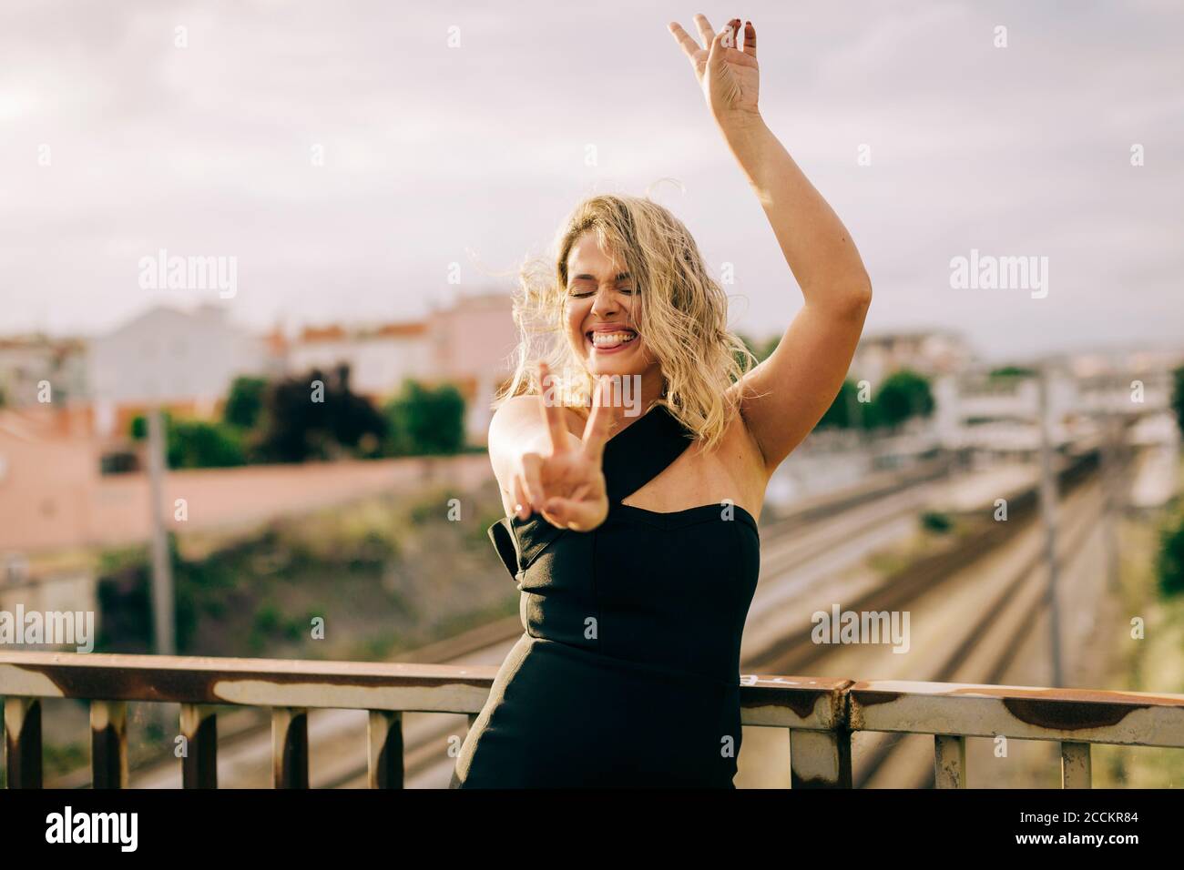 Donna allegra che mostra il segno di pace in città Foto Stock