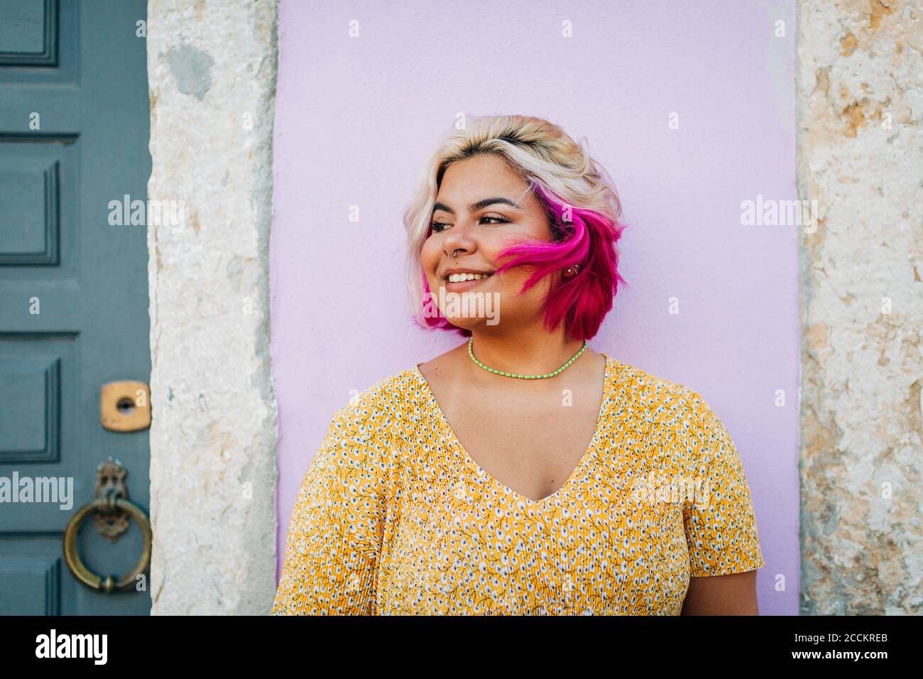 Donna sorridente più grande in piedi contro il muro Foto Stock