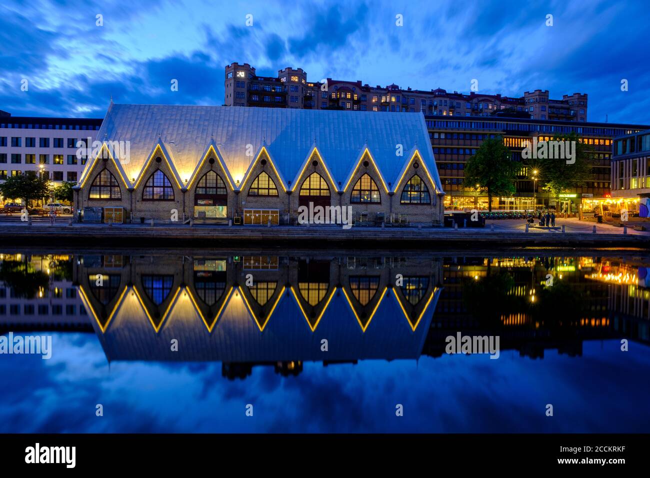 Svezia, Vastra Gotaland County, Goteborg, Feskekorka mercato del pesce che riflette nelle acque costiere al crepuscolo Foto Stock