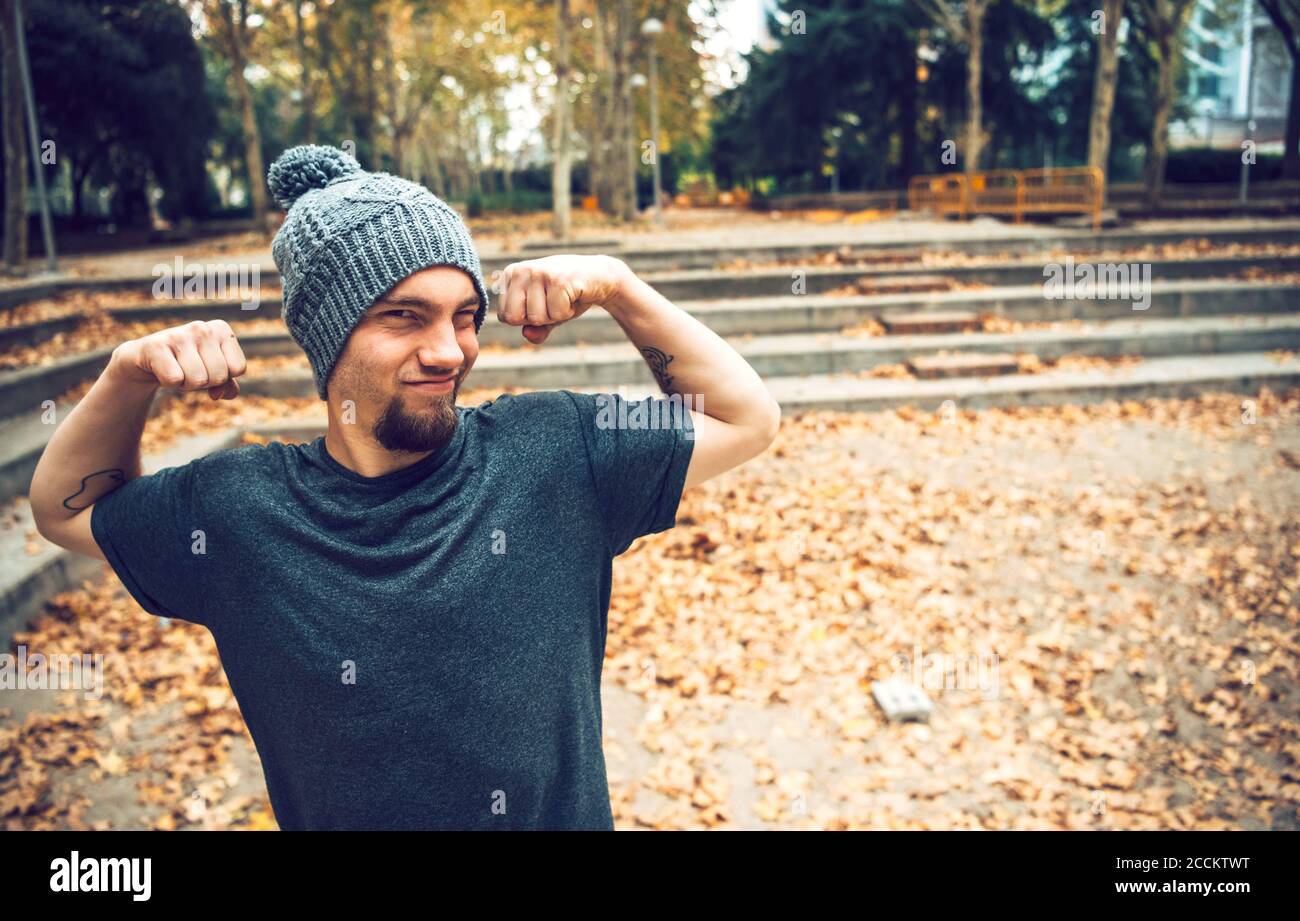 Uomo che flette i muscoli mentre si trova in parcheggio durante l'autunno Foto Stock