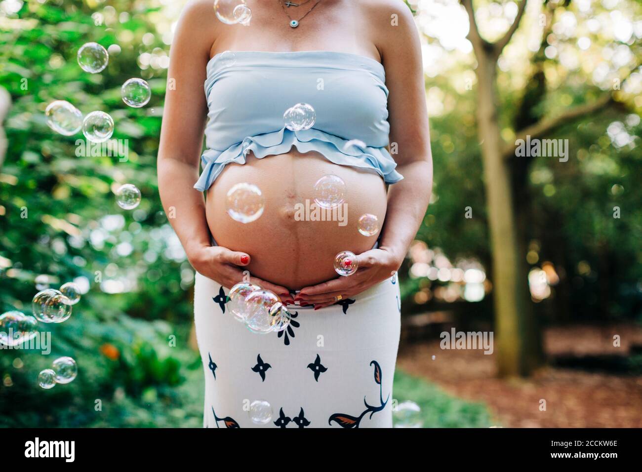 Donna incinta che tocca il ventre mentre si trova in posizione di parcheggio Foto Stock