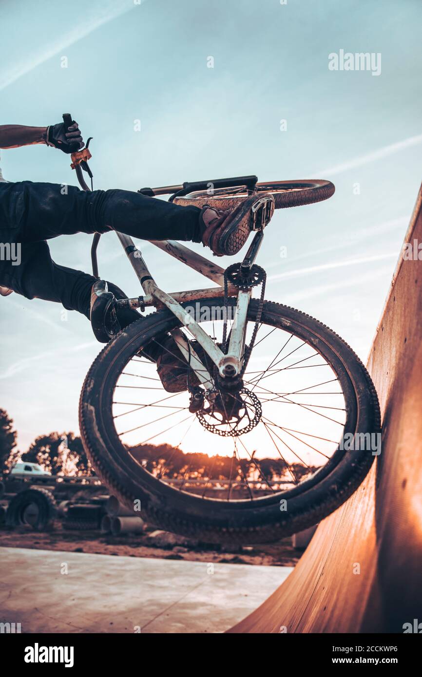 Giovane uomo in bicicletta sulla rampa nel parco durante il tramonto Foto Stock