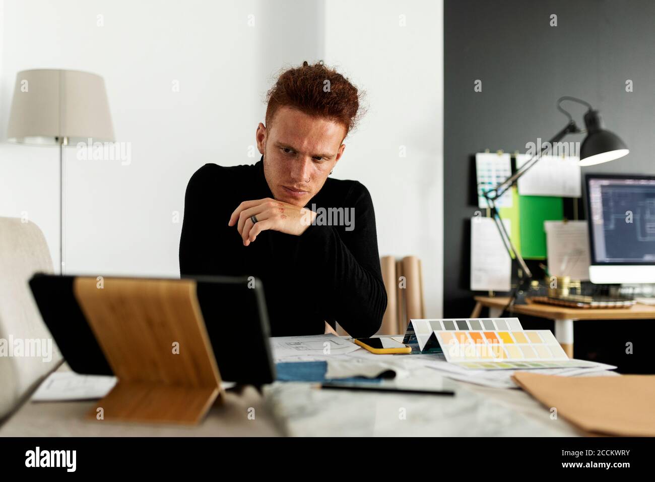 Architetto attento che guarda al tablet digitale in ufficio domestico Foto Stock