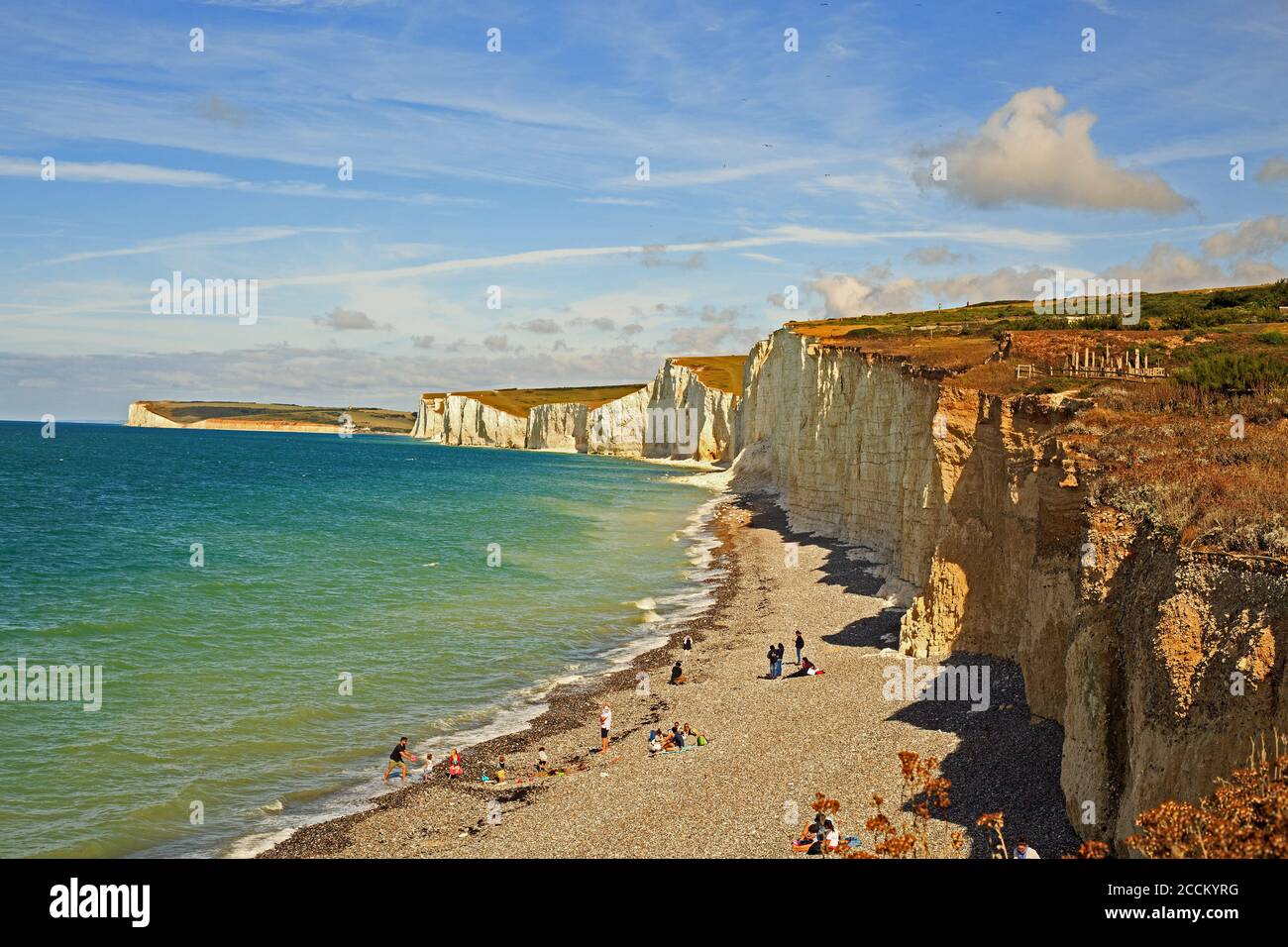 Seven Sisters Cliff, Regno Unito, 2020. I turisti che si godono la spiaggia di ciottoli in un giorno estivo dopo il blocco. Le scogliere sono gesso e si trovano al bordo Foto Stock