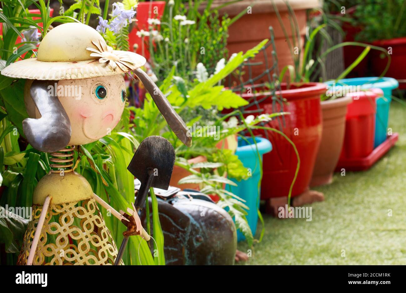 Carino ornamento Giardino di sorridente ragazza con una fila di vasi da fiori colorati sullo sfondo Foto Stock