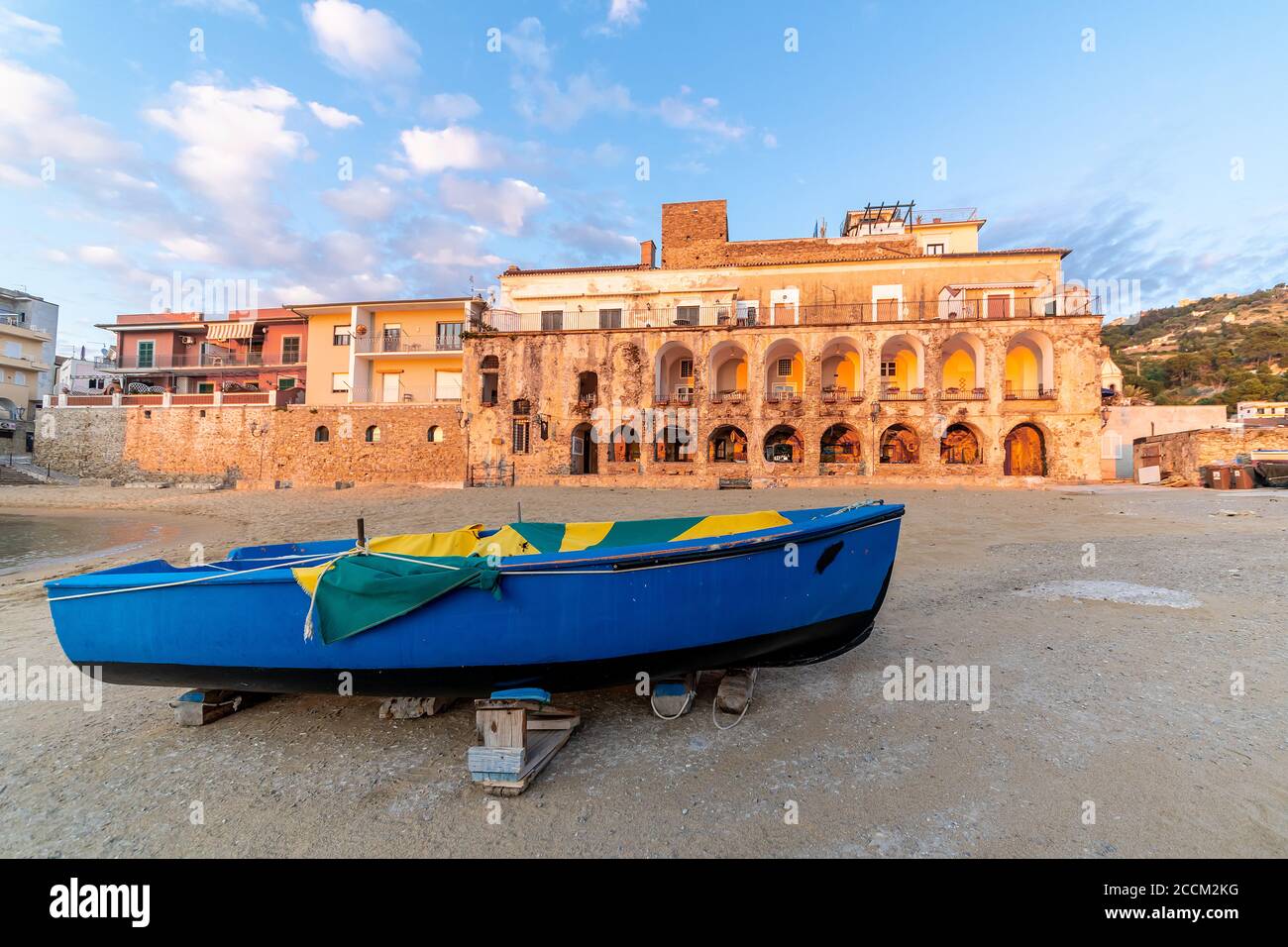 Antico edificio al tramonto a Santa Maria di Castellabate, Costa del Cilento, Italia. Luogo famoso, vista grandangolare con una barca in primo piano. Foto di alta qualità Foto Stock