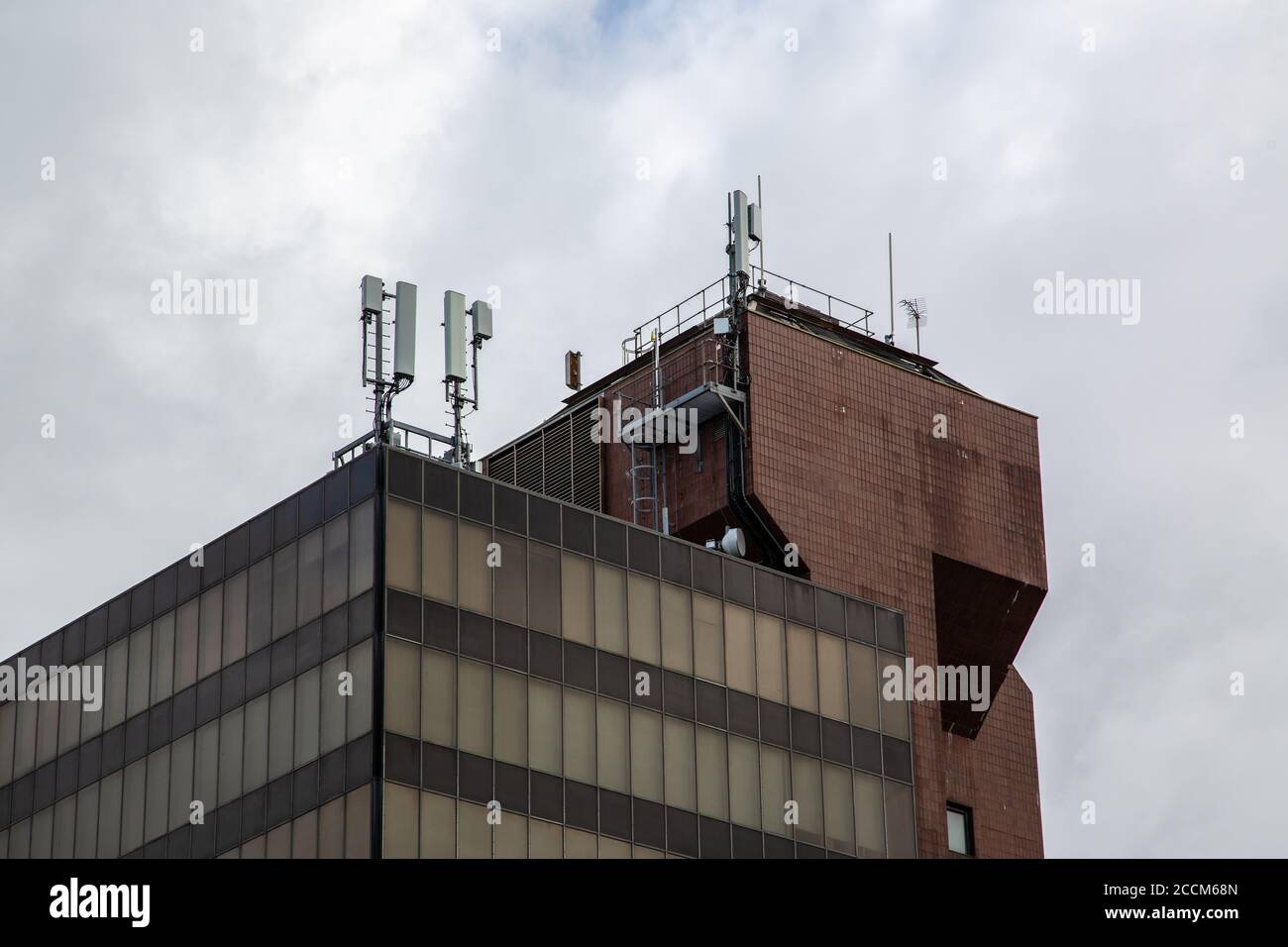 Un edificio per uffici con antenne per telefoni cellulari e montanti il tetto Foto Stock