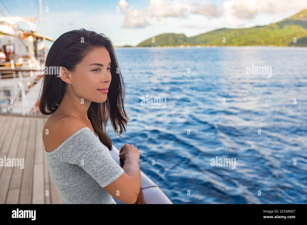 Nave da crociera di lusso vacanza viaggio donna barca passeggero che guarda il tramonto dal ponte. Bella ragazza turistica asiatica rilassante all'esterno godendo di vista Foto Stock