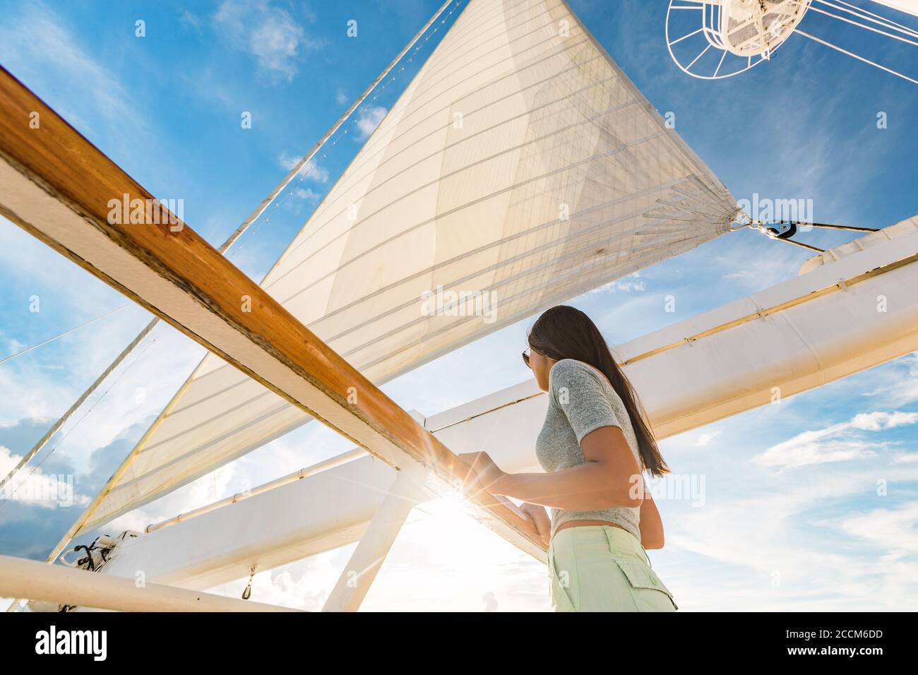 Donna di vacanza di lusso della nave da crociera sul ponte dello yacht al tramonto. Viaggio in Tahiti vela e albero su cielo. Il passeggero in barca si allontana per una fuga tropicale Foto Stock