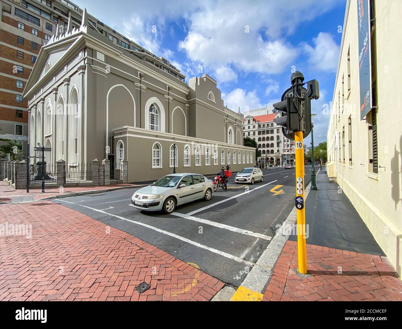 CITTÀ DEL CAPO, SUD AFRICA - 13 maggio 2020: Un autista di consegna in attesa al semaforo con Groote Kerk su Adderley Street in background durante il c. Foto Stock