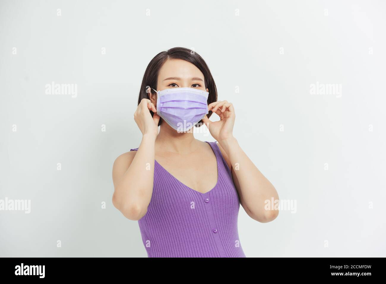 Donna incinta asiatica indossare maschera viso tenendo il ventre, guardare la fotocamera, isolato su sfondo bianco, covid-19 concetto Foto Stock