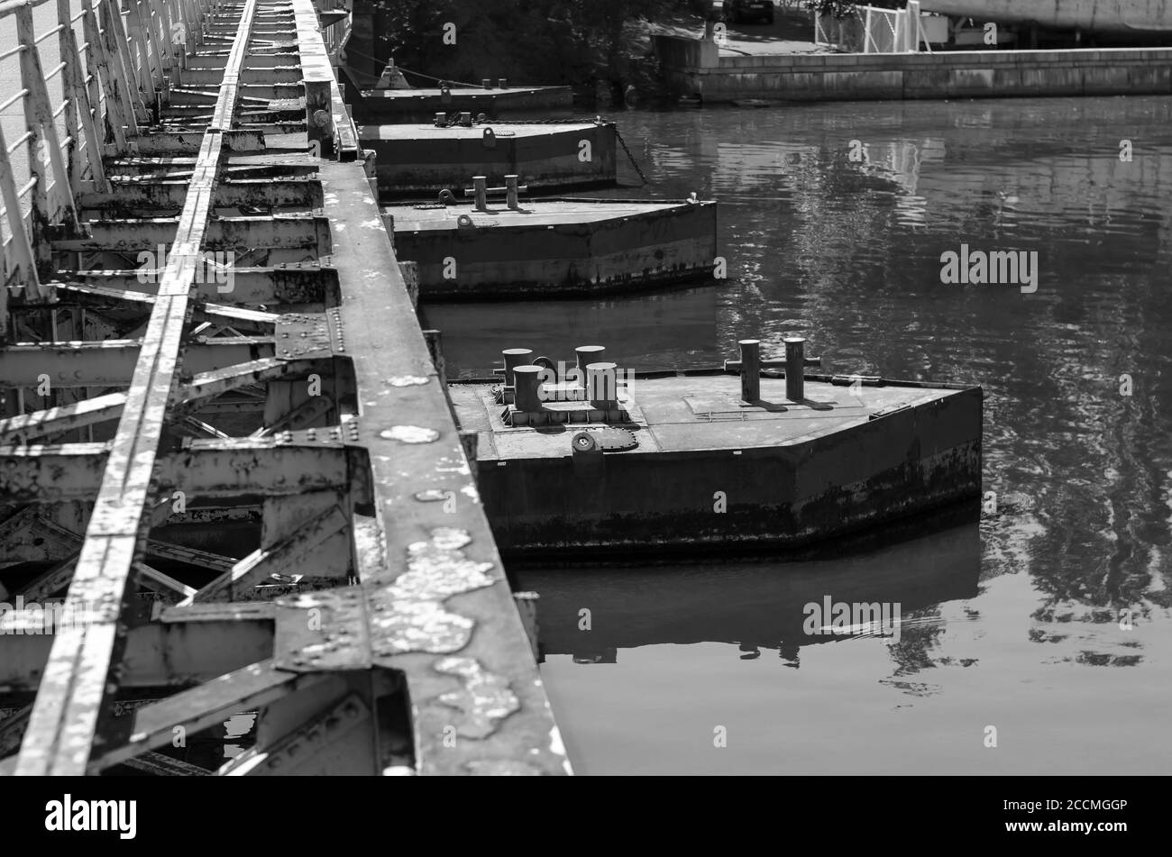 Vecchio ponte di metallo arrugginito sul fiume. Quattro laghetti con frangiflutti, catene di ancoraggio e paletti. Frammento della parte esterna del vecchio ponte Foto Stock