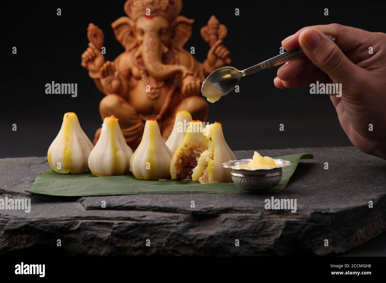 Modak - piatto tradizionale preparato con il festival di Ganpati in India, servito con burro chiarificato. Idolo Ganesh sullo sfondo Foto Stock