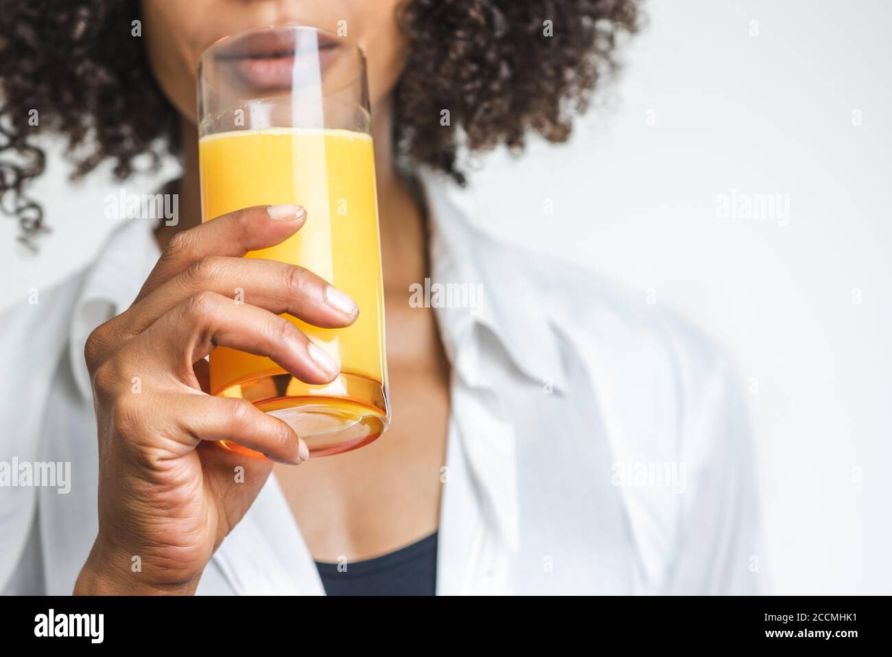 mano di una donna afro americana che tiene un bicchiere di succo d'arancia Foto Stock