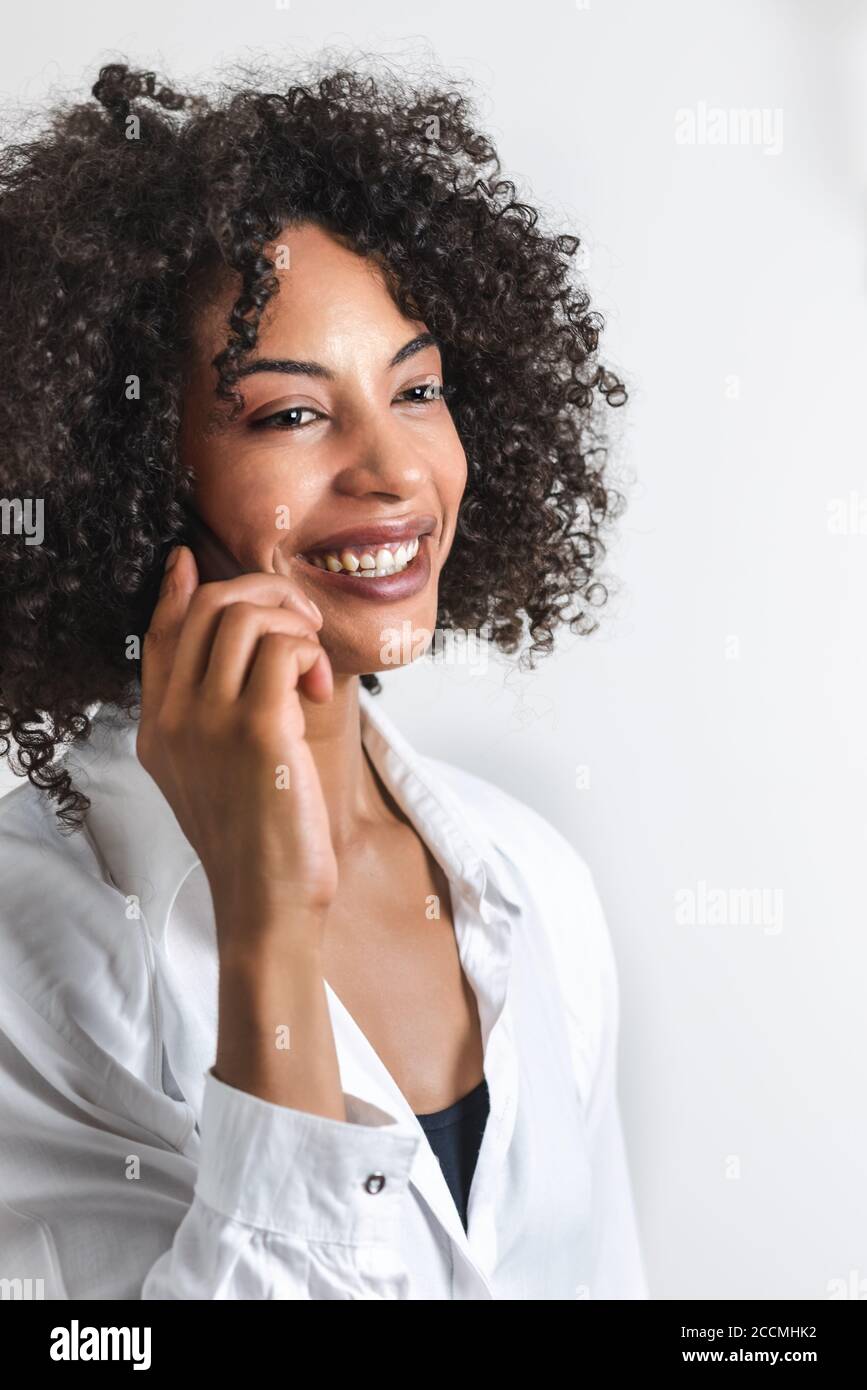 ritratto verticale di una donna afro che sorride mentre tiene un telefono Foto Stock