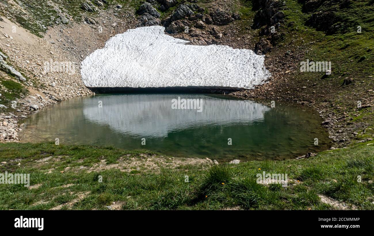 Lago glaciale di ghiaccio fondente di ghiacciai, rocce e terre in estate. Parzialmente congelato. Paesaggio in Valle d'Aosta in Italia. Cambiamenti climatici e envi Foto Stock