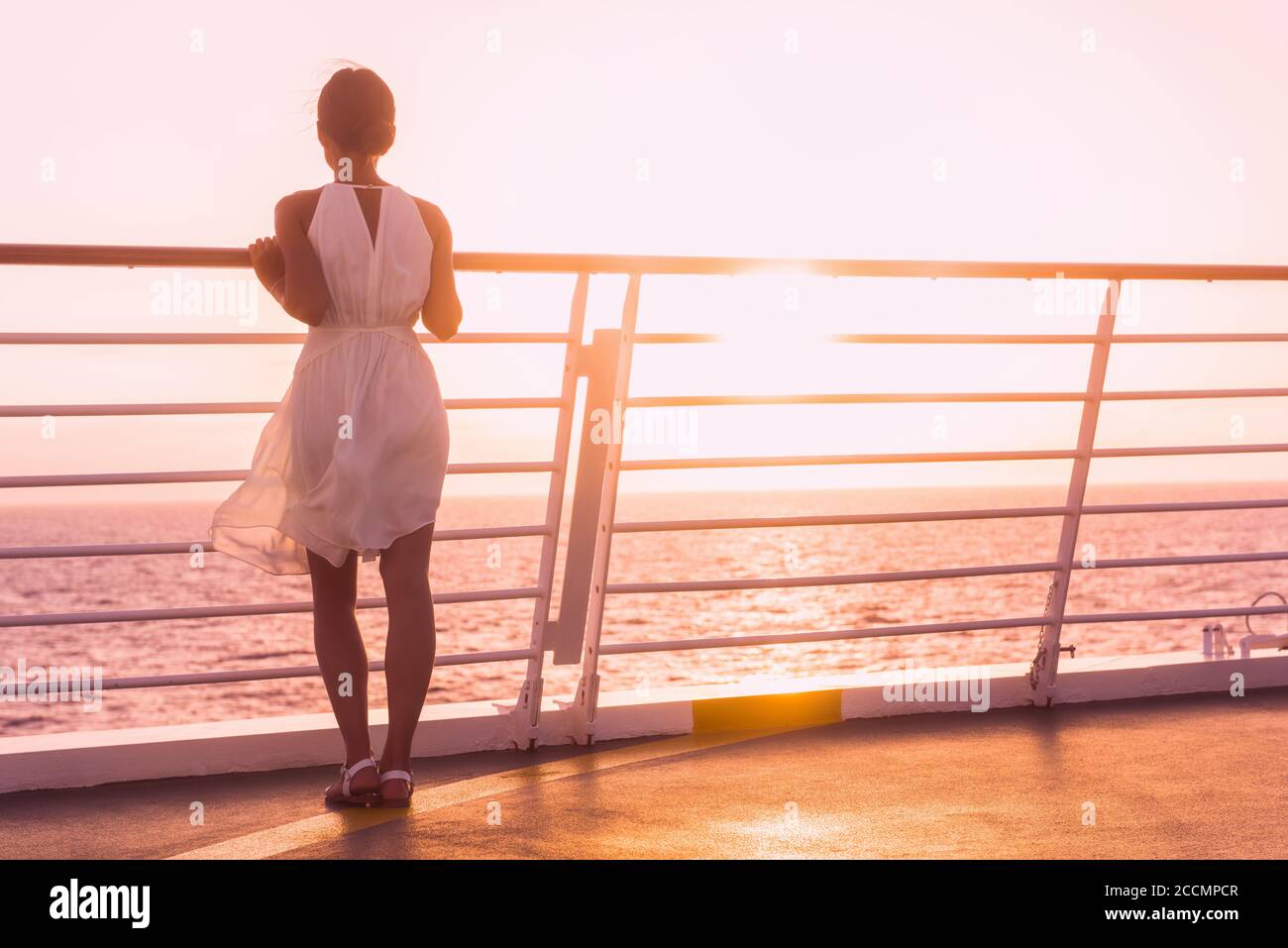 Crociera nave vacanza donna viaggio di lusso guardando il tramonto sull'oceano . Elegante donna in abito bianco sul ponte godendo di vista della famosa destinazione di vacanza Foto Stock