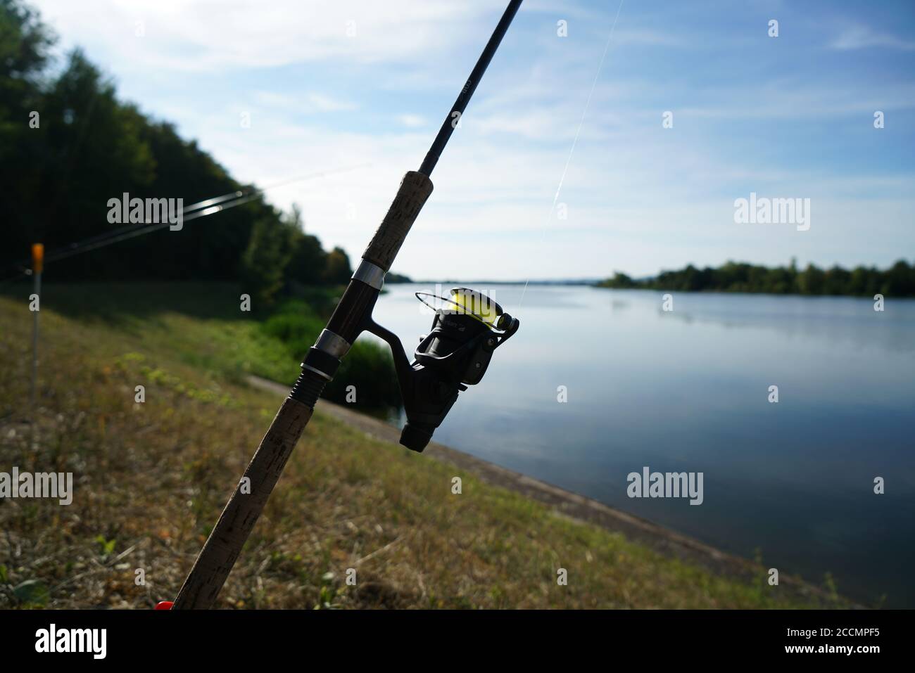 Primo piano di una canna da pesca presso il lago sotto un cielo nuvoloso Foto Stock