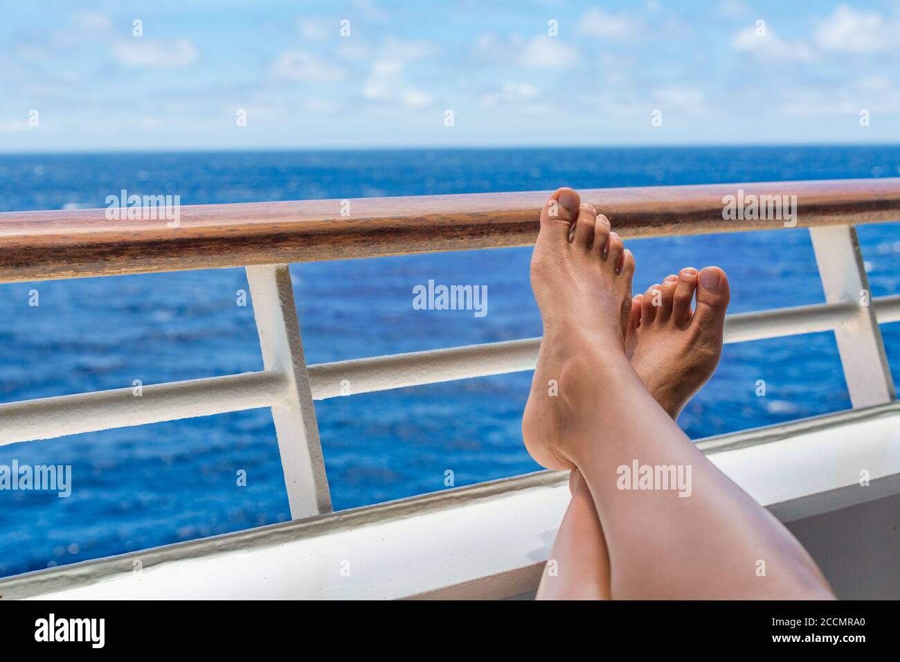 Crociera vacanza donna di viaggio relax con piedi sul balcone ponte nave godere vista oceano di destinazione di vacanza. Primo piano di gambe e ringhiera. Foto Stock