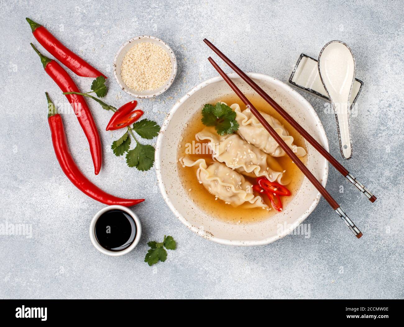 Zuppa calda fresca con gnocchi (gedza, wontons) di pollo, maiale o gamberetti con salsa di soia, peperoncino, coriandolo e semi di sesamo in un piatto bianco Foto Stock