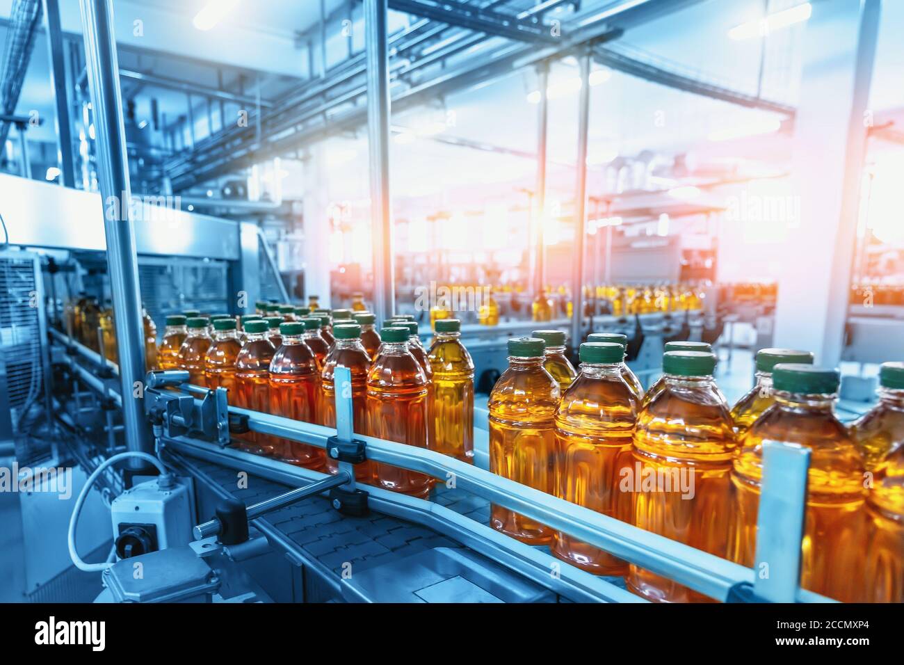 Interni in fabbrica con linea di produzione industriale, nastro trasportatore con succo in bottiglie. Foto Stock