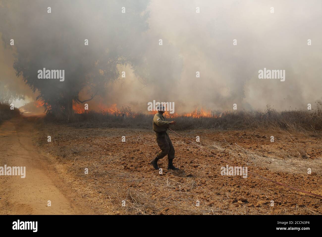 Am. NIR 23 agosto 2020. Un soldato israeliano cerca di estinguere il fuoco in un'area vicina al confine tra Israele e la striscia di Gaza vicino a Kibbutz di NIR am, il 23 agosto 2020. Dal 6 agosto Gaza ha assistito a tensioni militari con l'esercito israeliano, poiché i giovani palestinesi stanno ripristinando il lancio di palloncini incendiari verso le città israeliane adiacenti alla striscia. Di conseguenza, gli aerei da guerra israeliani hanno preso di mira decine di siti militari appartenenti al movimento di Hamas, in risposta al lancio di palloncini arson. Credit: Gil Cohen Magen/Xinhua/Alamy Live News Foto Stock