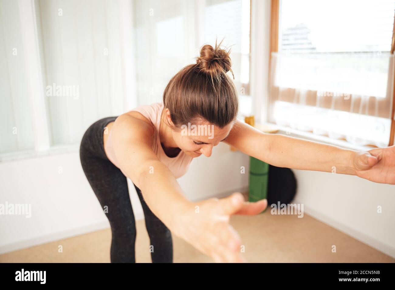 Donna bruna caucasica in forma e sana che si piega in avanti con sollevata armi a casa Foto Stock