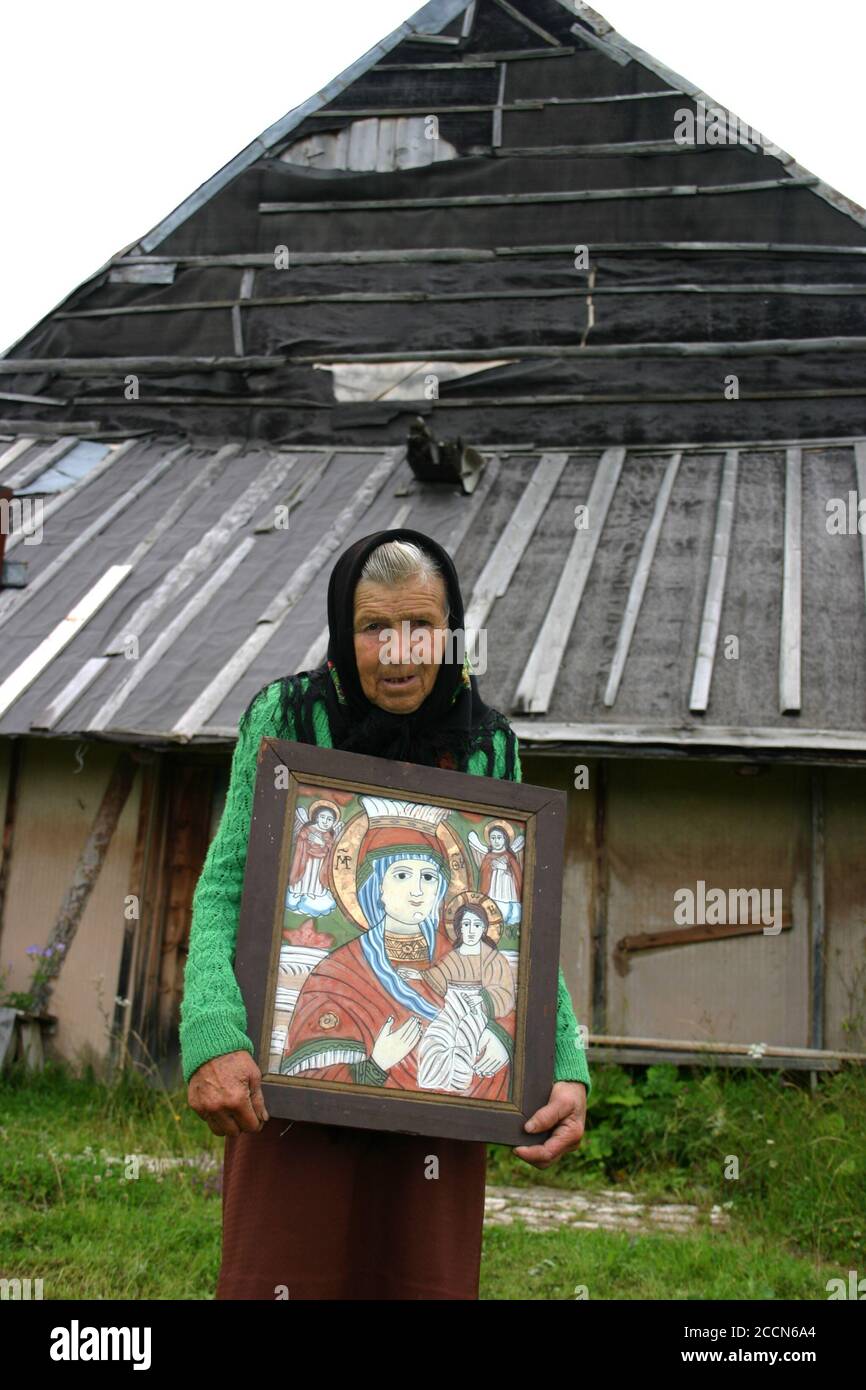 Vecchia donna nella campagna rumena con un'icona bizantina dipinta a mano su vetro Foto Stock