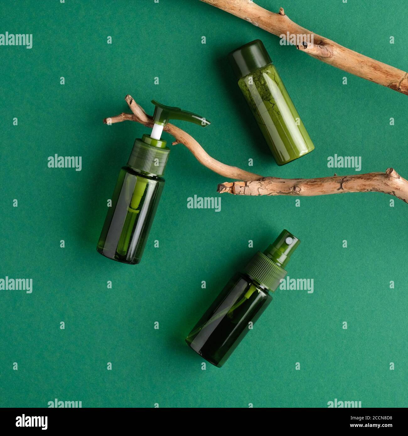 SPA prodotti naturali di bellezza biologica design di confezionamento. Posa piatta, vista dall'alto bottiglie cosmetiche verdi e ramo in legno su sfondo verde Foto Stock