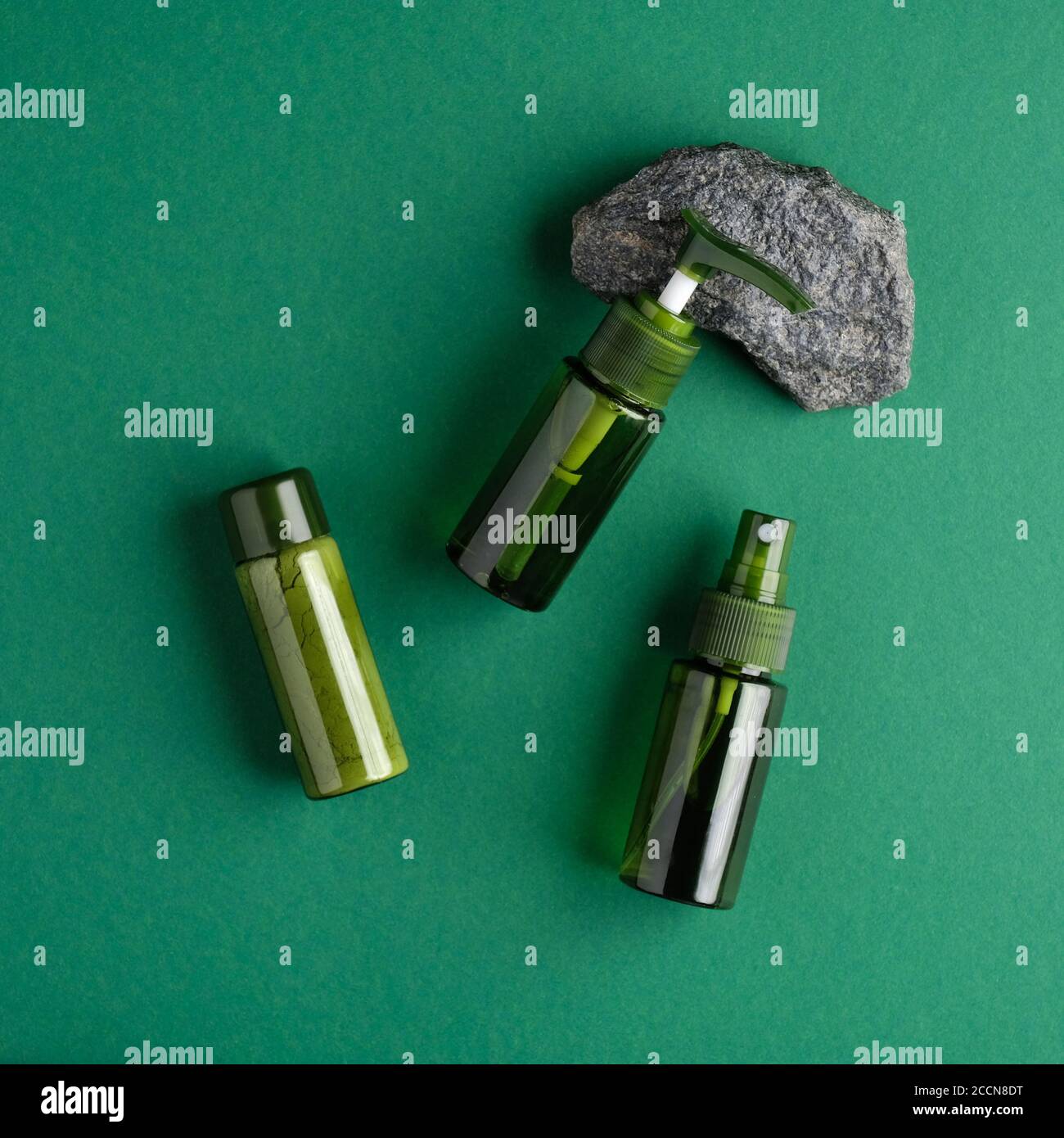SPA prodotti naturali di bellezza biologica design di confezionamento. Bottiglie di cosmetici verdi e pietra su sfondo verde. Disposizione piatta, vista dall'alto Foto Stock